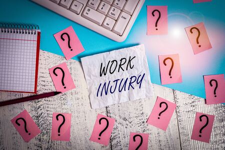 Handwriting text writing Work Injury. Conceptual photo illness caused by events or exposures in the work environment Writing tools, computer stuff and math book sheet on top of wooden tableの写真素材