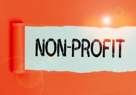 Text sign showing Non Profit. Business photo text not making or conducted primarily to make profit organization Cardboard which is torn in the middle placed above a plain table backdropの写真素材