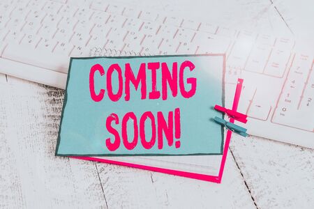 Handwriting text Coming Soon. Conceptual photo event or action that will happen after really short time notebook paper reminder clothespin pinned sheet white keyboard light woodenの写真素材