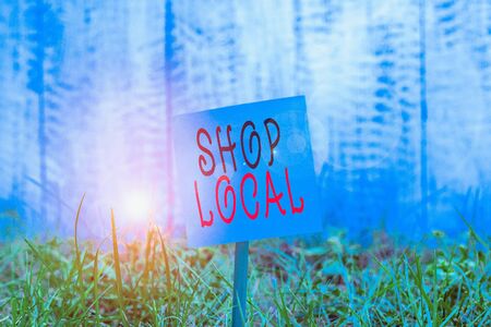 Text sign showing Shop Local. Business photo showcasing a preference to buy locally produced goods and services Plain empty paper attached to a stick and placed in the green grassy landの写真素材