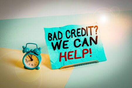 Writing note showing Bad Credit Question We Can Help. Business concept for offering help after going for loan then rejected Alarm clock beside a Paper sheet placed on pastel backdropの写真素材