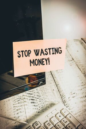 Word writing text Stop Wasting Money. Business photo showcasing advicing demonstrating or group to start saving and use it wisely Notation paper taped to black computer monitor screen near white keyboardの写真素材