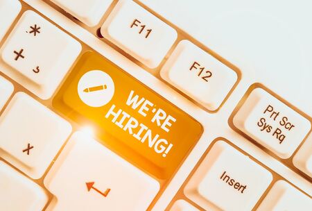 Text sign showing We Are Re Hiring. Business photo text process of reviewing applications and finding candidates White pc keyboard with empty note paper above white background key copy spaceの写真素材
