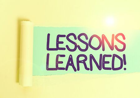 Handwriting text Lessons Learned. Conceptual photo experiences distilled project that should actively taken Cardboard which is torn in the middle placed above a plain table backdropの写真素材