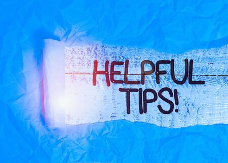 Text sign showing Helpful Tips. Business photo text advices given to be helpful knowledge in life Cardboard which is torn in the middle placed above a wooden classic tableの写真素材