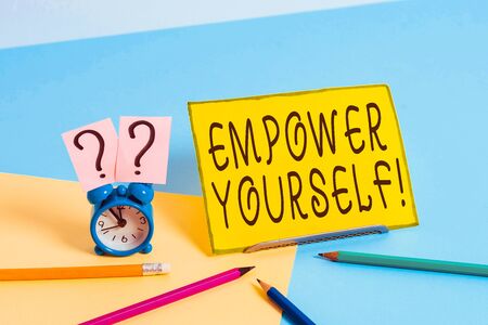 Conceptual hand writing showing Empower Yourself. Concept meaning taking control of our life setting goals and making choices Mini size alarm clock beside stationary on pastel backdropの写真素材