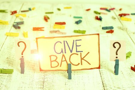 Word writing text Give Back. Business photo showcasing the act of giving someone something that they owned or had before Scribbled and crumbling sheet with paper clips placed on the wooden tableの写真素材