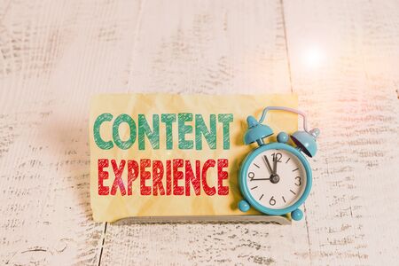 Word writing text Content Experience. Business photo showcasing environment in which content lives and structured Mini blue alarm clock stand tilted above buffer wire in front of notepaperの写真素材