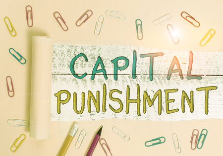 Text sign showing Capital Punishment. Business photo showcasing authorized killing of someone as punishment for a crime Stationary and torn cardboard placed above a wooden classic table backdropの写真素材