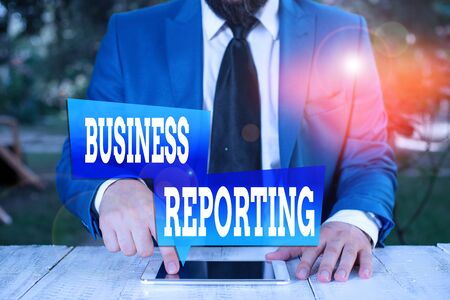 Word writing text Business Reporting. Business photo showcasing a formal written document for a business setting Businessman in blue suite with a tie holds lap top in handsの写真素材