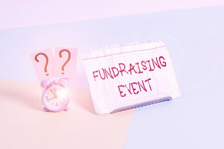 Text sign showing Fundraising Event. Business photo text campaign whose purpose is to raise money for a cause Mini size alarm clock beside a Paper sheet placed tilted on pastel backdropの写真素材