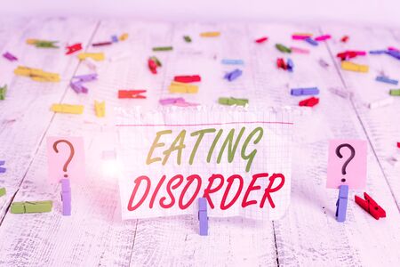 Writing note showing Eating Disorder. Business concept for illnesses that are characterized by irregular eating habits Crumbling sheet with paper clips placed on the wooden tableの写真素材