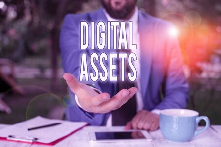 Word writing text Digital Assets. Business photo showcasing has value and can be owned but has no physical presence Man with opened hands in fron of the table. Mobile phone and notes on the tableの写真素材