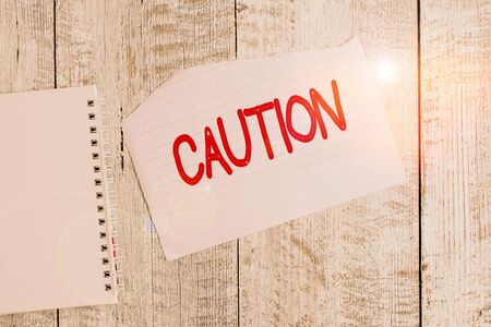 Conceptual hand writing showing Caution. Concept meaning Care taken to avoid danger or mistakes Warning sign Prevention Torn paper and notebook sheet placed above classic wooden tableの写真素材
