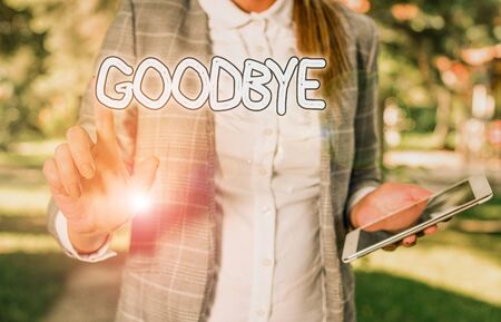 Conceptual hand writing showing Goodbye. Concept meaning used to express good wishes when parting or end of a conversation Business woman sitting with mobile phone and cup of coffeeの写真素材