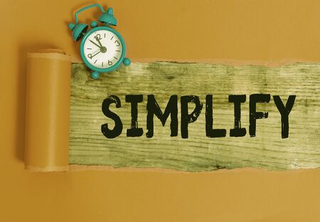 Handwriting text writing Simplify. Conceptual photo make something simpler or easier to do or understand unravel Alarm clock and torn cardboard placed above a wooden classic table backdropの写真素材