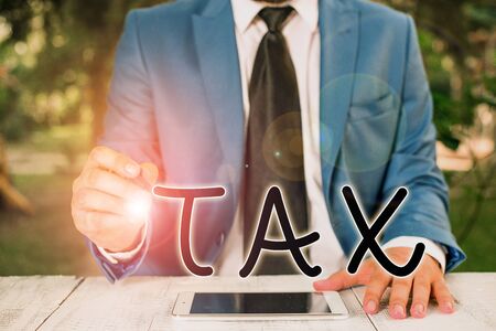Handwriting text writing Tax. Conceptual photo Compulsory contribution to state revenue Levy impose by government Businessman holds pen and points into copy spaceの写真素材