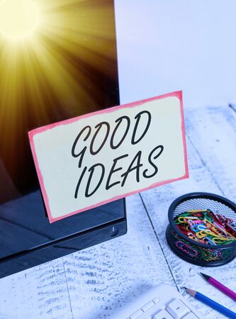 Writing note showing Good Ideas. Business concept for nice formulated thought or opinion Best possible course of action Note paper taped to black computer screen near keyboard and stationaryの写真素材