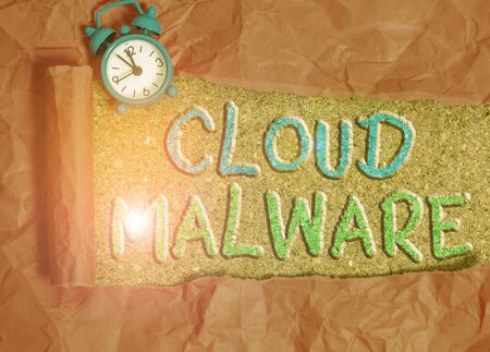 Text sign showing Cloud Malware. Business photo showcasing malicious software file or program harmful to a computer Alarm clock and torn cardboard placed above a wooden classic table backdropの写真素材