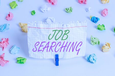 Handwriting text writing Job Searching. Conceptual photo The act of looking for employment Job seeking or job hunting Colored crumpled papers empty reminder white floor background clothespinの写真素材