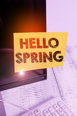 Word writing text Hello Spring. Business photo showcasing welcoming the season of the blossoming of flowers End of winter Notation paper taped to black computer monitor screen near white keyboardの写真素材