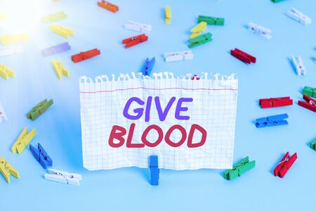 Conceptual hand writing showing Give Blood. Concept meaning demonstrating voluntarily has blood drawn and used for transfusions Colored clothespin paper empty reminder blue floor officepinの写真素材