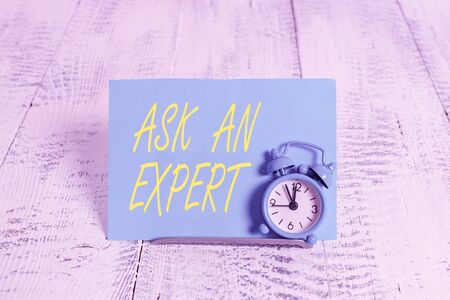 Handwriting text Ask An Expert. Conceptual photo confirmation that have read understand and agree with guidelines Mini blue alarm clock stand tilted above buffer wire in front of notepaperの写真素材
