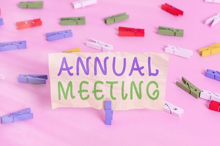 Text sign showing Annual Meeting. Business photo showcasing yearly meeting of the general membership of an organization Colored clothespin papers empty reminder pink floor background office pinの写真素材