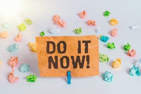 Conceptual hand writing showing Do It Now. Concept meaning not hesitate and start working or doing stuff right away Colored crumpled paper empty reminder white floor clothespinの写真素材