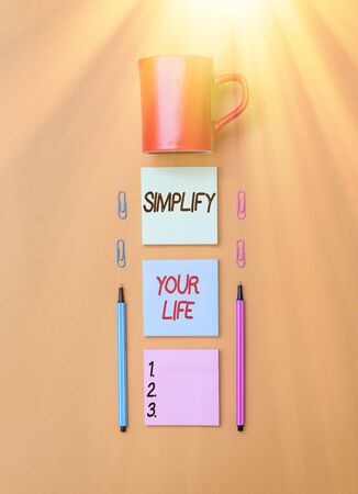 Handwriting text writing Simplify Your Life. Conceptual photo focused on important and let someone else worry about less ones Coffee cup blank colored sticky note two ballpoints clips yolk backgroundの写真素材