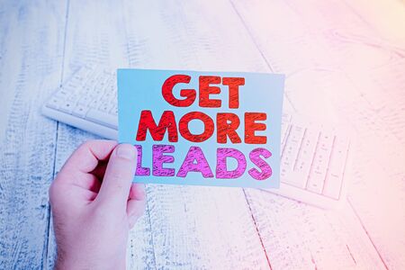 Handwriting text writing Get More Leads. Conceptual photo to have more customers and improve your target sales man holding colorful reminder square shaped paper white keyboard wood floorの写真素材