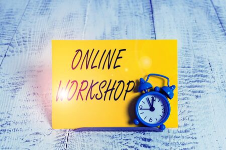 Writing note showing Online Workshop. Business concept for intensive discussion and activity on a particular subject Alarm clock tilted above buffer wire in front of notepaper