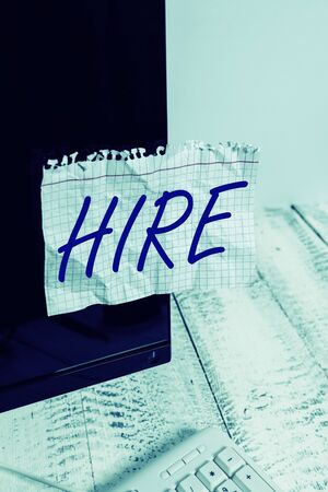 Text sign showing Hire. Business photo showcasing Employ someone or pay someone to do a particular job Employ for wages Notation paper taped to black computer monitor screen near white keyboardの写真素材