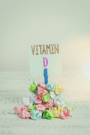 Text sign showing Vitamin D. Business photo showcasing Nutrient responsible for increasing intestinal absorption Reminder pile colored crumpled paper clothespin reminder white wooden spaceの写真素材