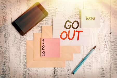 Word writing text Go Out. Business photo showcasing to leave a room or building, especially in order to do something Envelopes marker ruled paper smartphone sheet note pads wooden backgroundの写真素材