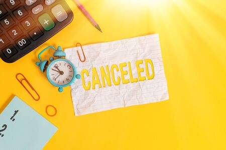 Text sign showing Canceled. Business photo text to decide not to conduct or perform something planned or expected Alarm clock clips note rubber band calculator pencil colored backgroundの写真素材