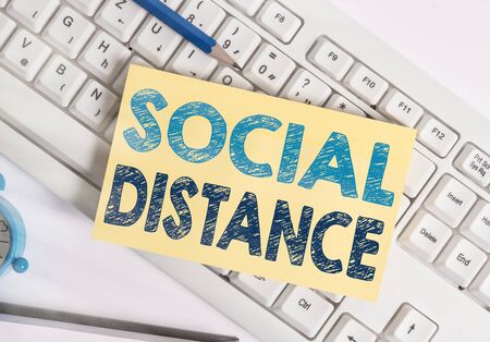 Writing note showing Social Distance. Business concept for degree of acceptance of general interaction of individuals White pc keyboard note paper and paper clips above white backgroundの写真素材