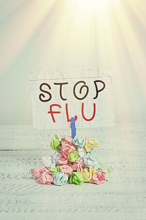 Handwriting text writing Stop Flu. Conceptual photo Treat the contagious respiratory illness caused by influenza virus Reminder pile colored crumpled paper clothespin reminder white wooden spaceの写真素材