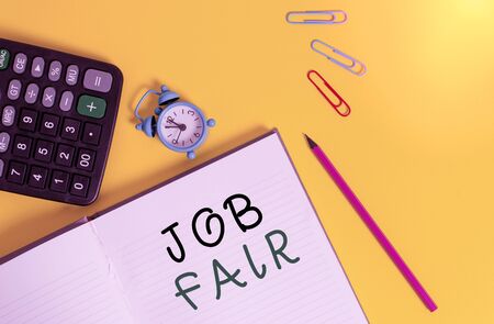 Word writing text Job Fair. Business photo showcasing event in which employers recruiters give information to employees Open striped notebook calculator clips pencil alarm clock color backgroundの写真素材