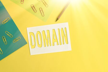 Word writing text Domain. Business photo showcasing an area of territory controlled by a particular ruler or government Blank paper sheets squared notebook pencil clips plain colored backgroundの写真素材