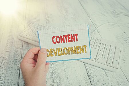 Text sign showing Content Development. Business photo text Specialized in Graphic Design Multimedia Documentation man holding colorful reminder square shaped paper white keyboard wood floorの写真素材