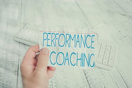 Conceptual hand writing showing Performance Coaching. Concept meaning Facilitate the Development Point out the Good and Bad Man holding colorful reminder square shaped paper wood floorの写真素材