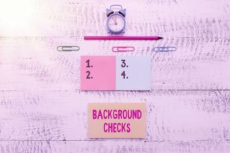 Writing note showing Background Checks. Business concept for looking up compiling criminal records for Organization Blank notepads clips marker small alarm clock wooden vintage backgroundの写真素材