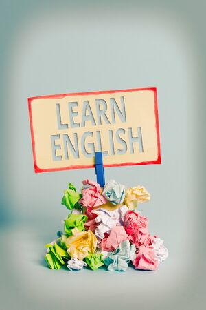 Text sign showing Learn English. Business photo text Universal Language Easy Communication and Understand Reminder pile colored crumpled paper clothespin reminder blue backgroundの写真素材