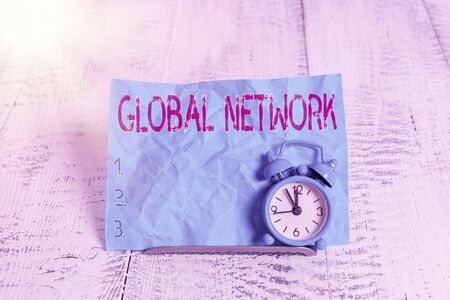Text sign showing Global Network. Business photo showcasing Any communication system which spans the entire Earth Mini blue alarm clock stand tilted above buffer wire in front of notepaperの写真素材