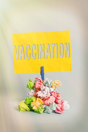 Handwriting text Vaccination. Conceptual photo Treatment which makes the body stronger against infection Reminder pile colored crumpled paper clothespin reminder blue backgroundの写真素材