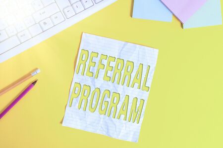 Word writing text Referral Program. Business photo showcasing internal recruitment method employed by organizations Copy space on notebook above yellow background with pc keyboard on the tableの写真素材