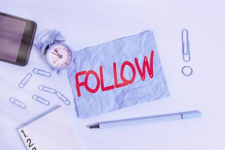 Conceptual hand writing showing Follow. Concept meaning to come after something in time or place or as part of a series Alarm clock notepad smartphone band marker colored backgroundの写真素材