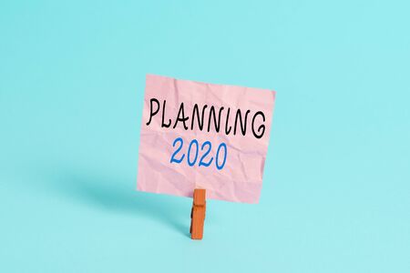 Writing note showing Planning 2020. Business concept for process of making plans for something next year Colored clothespin rectangle square shaped paper light blue backgroundの写真素材