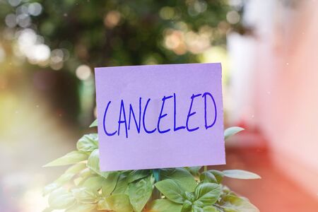 Handwriting text Canceled. Conceptual photo to decide not to conduct or perform something planned or expected Plain empty paper attached to a stick and placed in the green leafy plantsの写真素材